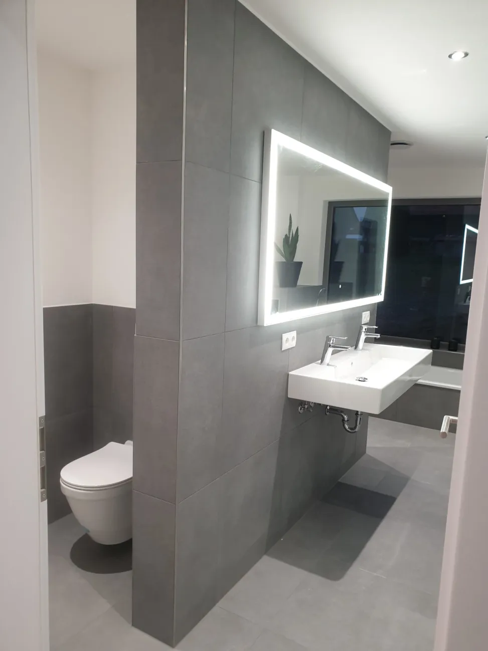 Modernes Badezimmer mit holzoptischen Fliesen und freistehender Wanne